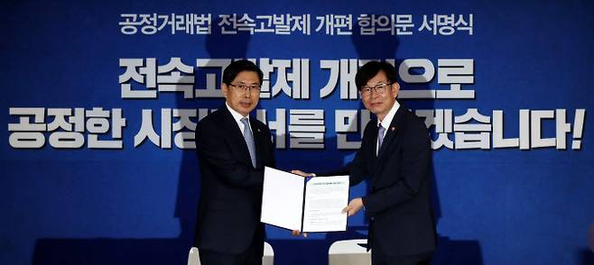 박상기(왼쪽) 법무부 장관과 김상조 공정거래위원장이 2018년 8월 오전 서울 종로구 세종대로 정부서울청사 브리핑룸에서 공정거래법 전속고발제 개편 합의문 서명식을 마치고 기념촬영을 하고 있다. 하지만 전속고발권은 검경수사권 조정과 맞물려 현행대로 공정위가 보유하는 것으로 결론이 났다.(사진 = 뉴시스)