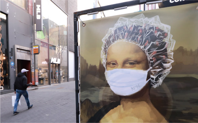 2월 8일 서울 중구 명동 거리에 한 시민이 지나가고 있다. 거리에 세워진 미용실 광고판에는 마스크와 비닐캡을 쓴 모나리자 그림이 그려져 있다. [동아일보 송은석 기자]