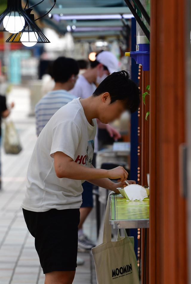 서울 동작구 노량진 컵밥 거리에서 한 청년이 손에 가방을 든 채 컵밥을 먹고 있다. 최현규 기자