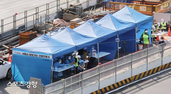 코로나19 신규 확진자가 2434명으로 역대 최다를 기록한 24일 서울역 앞 공사장에 마련된 서울시 찾아가는 선별진료소에서 공사 관계자들이 코로나19 검사를 하고 있다.  강윤중 기자