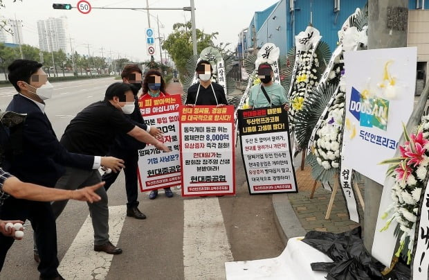 두산인프라코어 소액주주모임 회원들이 지난 10일 오전 인천시 동구 두산인프라코어 앞에서 경영진과 인수자인 현대제뉴인을 규탄하며 계란을 던지는 퍼포먼스를 벌이고 있다. /사진=연합뉴스