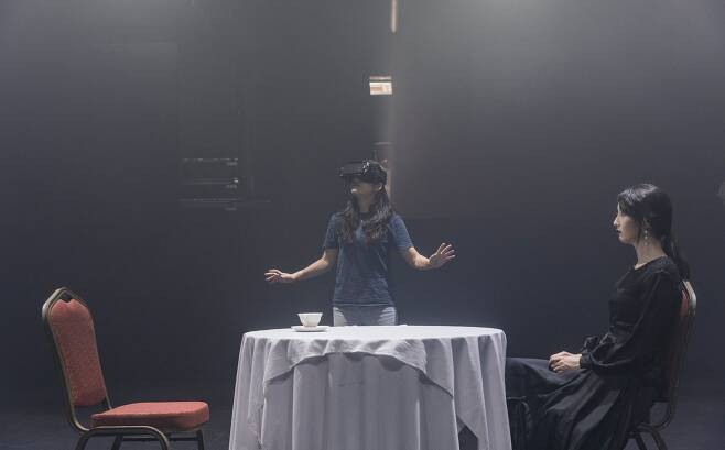 1인을 위한 연극 '코오피와 최면약'. 관객(왼쪽)은 혼자 VR 고글을 쓰고 가상현실로 들어간다. 오른쪽 여인은 가상현실에만 존재하는 헛것이다. /국립극단