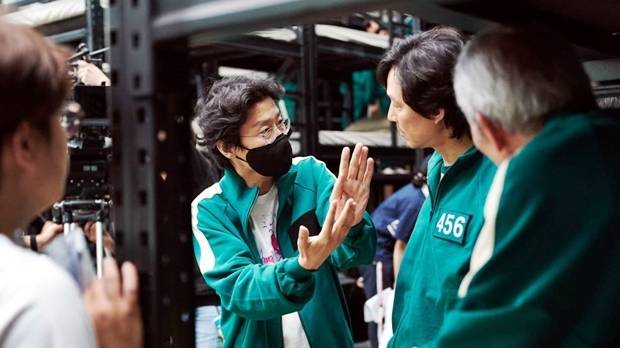 `오징어게임` 황동혁 감독(가운데)이 촬영장에서 이정재에 설명하고 있다. 제공|넷플릭스