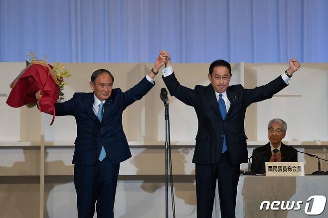 기시다 후미오 자민당 전 정무조사회장이 29일(현지시간) 도쿄에서 열린 집권 자민당 총재 선거에서 승리한 후 스가 요시히데 현 총리와 만세를 하고 있다. © AFP=뉴스1 © News1 금준혁 기자