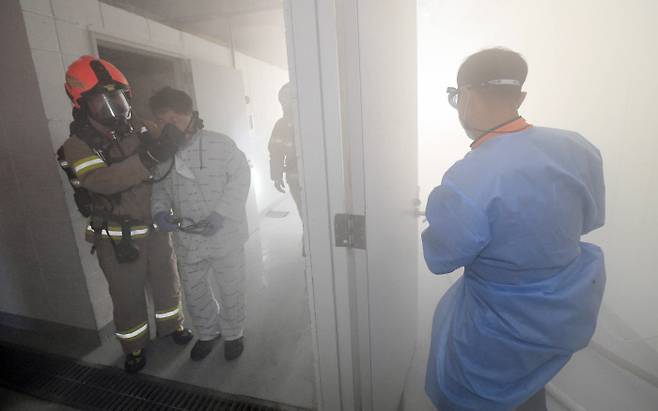 30일 서울 은평구 서울소방행정타운에서 열린 코로나19 관련 시설 화재 대비 및 특수사고 대응 종합훈련에서 구조대원들이 코로나 중증 환자 역할의 참가자를 구조하는 훈련을 하고 있다. 공동취재