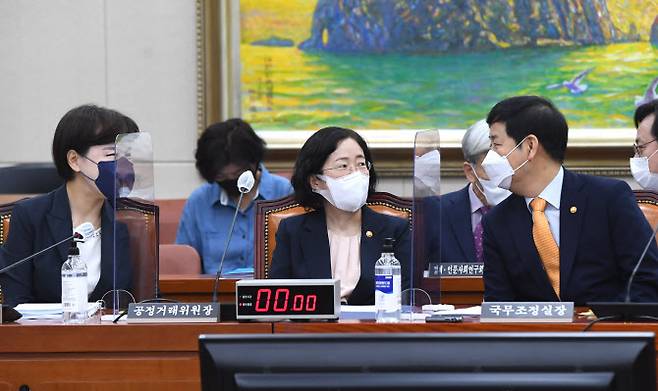 조성욱 공정거래위원장(가운데)이 지난달 국회 정무위 전체회의에서 구윤철 국무조정실장(오른쪽)과 대화를 하고 있다. (사진 = 연합뉴스)