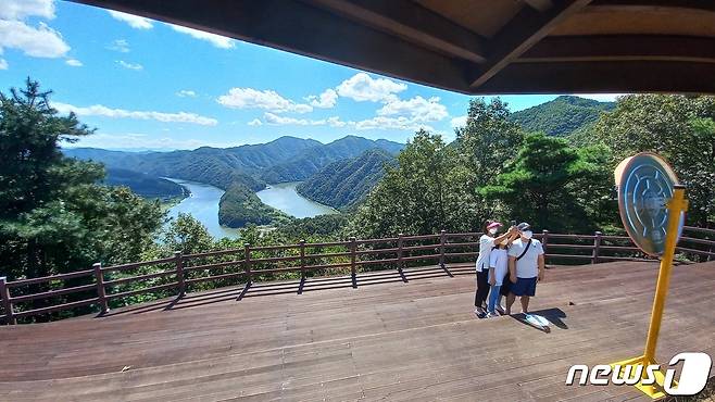 가족단위 관광객이 충북 옥천의 둔주봉 한반도 지형을 배경으로 기념촬영하고 있다. © 뉴스1