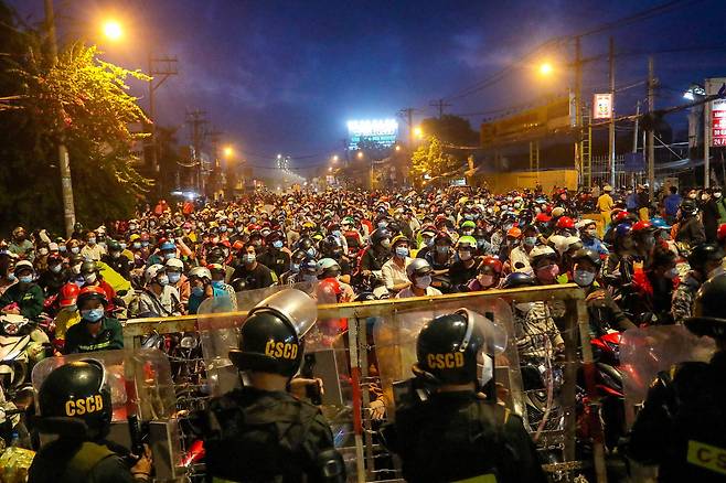 10월 1일 베트남 호찌민시 인근의 검문소에서 도시를 벗어나려는 시민들이 경찰과 대치하고 있다. 호찌민시는 지난 7월 코로나 델타 변이가 확산된후 시민들의 이동을 엄격하게 통제했다. 시 당국이 1일부터 봉쇄조치를 완화하겠다고 밝히자 다른 지역에서 왔다가 발이 묶인 이들이 고향으로 돌아가기 위해 검문소 앞으로 몰려들었다./ AFP 연합뉴스.