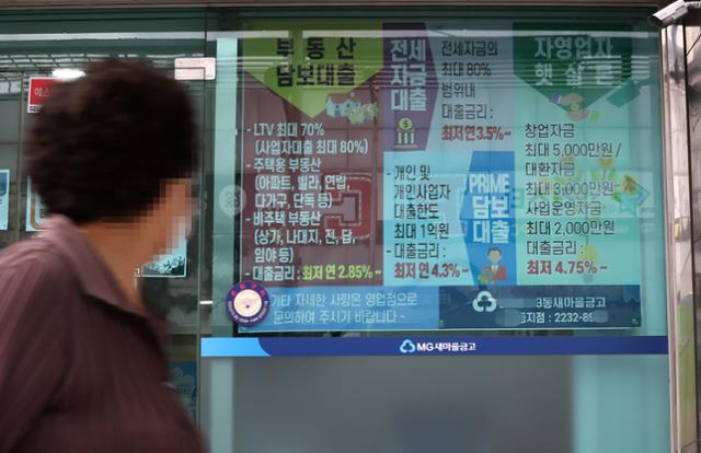 지난달 29일 오후 서울 시내 새마을금고 앞을 지나는 한 시민이 대출 관련 안내문을 읽고 있다. 연합뉴스