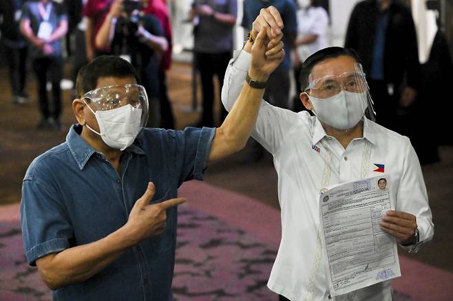 로드리고 두테르테 필리핀 대통령(왼쪽)이 2일(현지시간) 내년 선거에 부통령 후보로 등록한 크리스토퍼 봉 고 상원의원의 손을 들어 보이고 있다. 마닐라 | AP연합뉴스