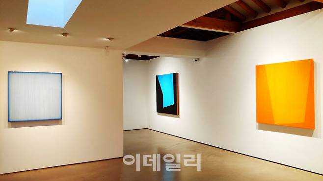 서울 종로구 삼청로 학고재갤러리 김현식 개인전 ‘현’(玄) 전경 중 일부. 왼쪽부터 ‘현을 보다 B’(2021·90×90×7cm)와 ‘보이는 것 너머’(2021·135×135×7㎝), ‘보이는 것 너머’(2021·120×120×7㎝). 오른쪽 두 작품 ‘보이는 것 너머’ 연작은 이번 개인전에서 처음 꺼내놓았다. “건물 사이로 보이는 하늘을 바라보는 시점을 녹여냈다”는 작품은 안쪽엔 레진 작업으로 하늘을, 바깥쪽은 아크릴물감만으로 단단한 건물 외형을 상징했다(사진=오현주 문화전문기자).