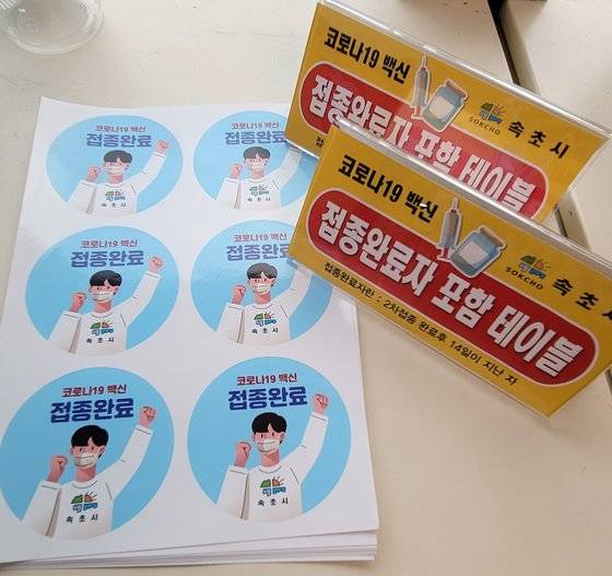 강원 속초시가 제작해 지역 내 업소에 배부한 '백신 접종자 포함된 테이블' 안내 표식과 접종자 식별 스티커. 연합뉴스