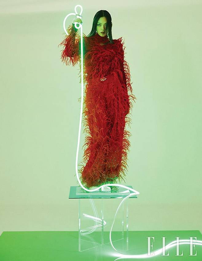 풍성한 깃털 장식의 레드 톱과 와이드 팬츠, 화이트 러버 부츠는 모두 Bottega Veneta.