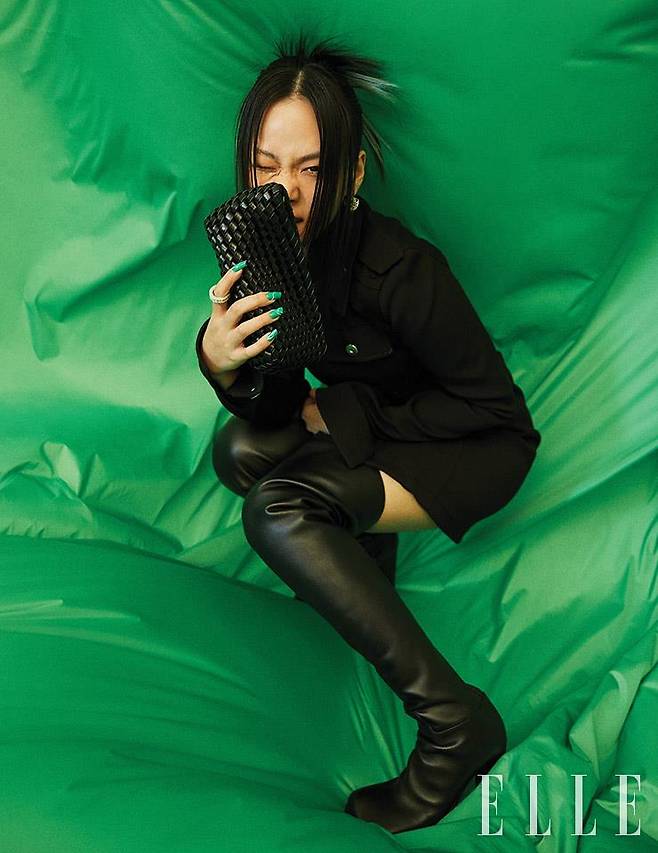 블랙 미니드레스와 아이코닉한 짜임이 돋보이는 스트럭처 클러치백, 사이하이 부츠 힐, 이어링, 링은 모두 Bottega Veneta.