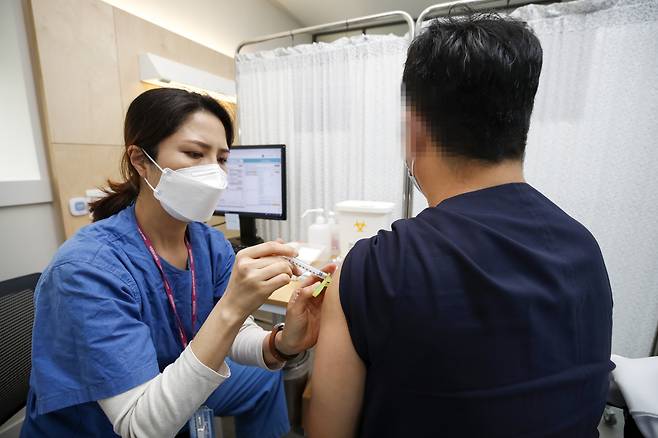 A health care worker at the National Medical Center in Seoul administers a dose of a COVID-19 vaccine on Tuesday. (Yonhap)