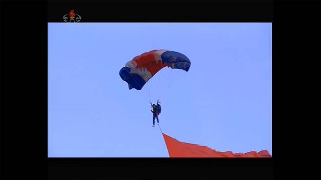 파란색 타이츠를 입은 '최우수 낙하산병'이 강하기교를 선보이고 있다.  (조선중앙TV 갈무리)© 뉴스1