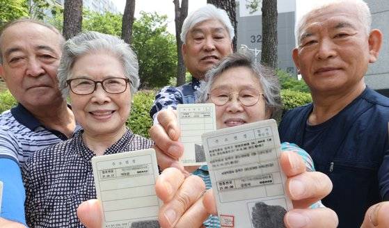 지난 7월 1일 서울 동작구 상도1동 주민센터에서 시민들이 코로나 예방접종스티커를 발급받아 신분증에 부착한 뒤 야외에서 마스크를 벗고 활짝 웃고 있다. 연합뉴스