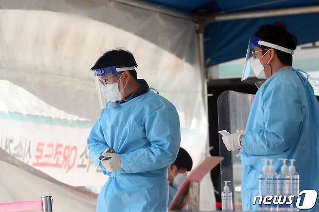 전국 대부분 지역에 한파경보와 한파주의보가 발표된 17일 오전 서울 중구 서울역광장에 마련된 신종 코로나바이러스 감염증(코로나19) 임시선별진료소에서 관계자가 핫팩으로 손을 녹이고 있다. 질병관리청 중앙방역대책본부는 이날 0시 기준 코로나19 신규 확진자가 1420명을 기록했다고 밝혔다. 2021.10.17/뉴스1 © News1 황기선 기자