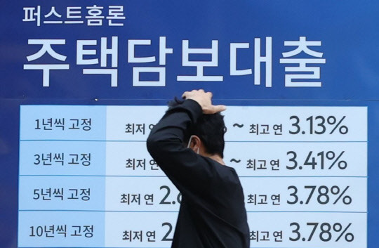 한 시민이 주택담보대출 안내가 걸린 은행 앞을 지나가고 있다. <연합뉴스>
