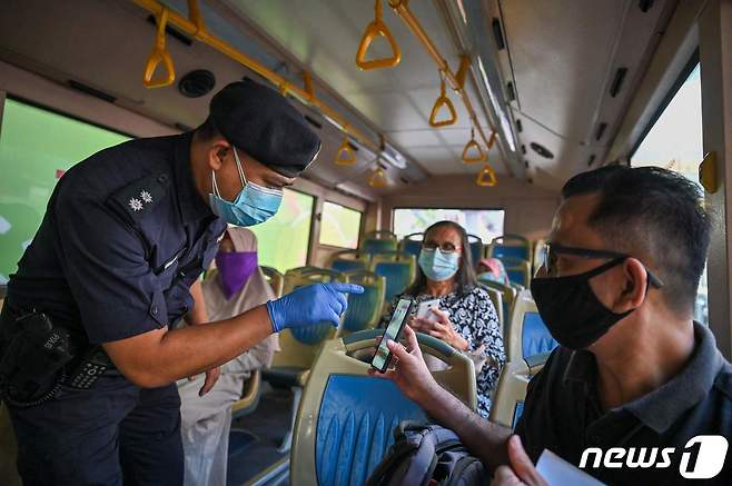 말레이시아의 전국 봉쇄 조치가 한창이던 지난 6월 1일 쿠알라룸푸르에서 경찰이 시민의 이동허가증을 검사하는 모습. © AFP=뉴스1