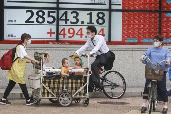 지난 11일 일본 도쿄에서 마스크를 쓴 시민들이 일본 주식시황을 알리는 전광판 앞을 지나고 있다. [AP=연합뉴스]