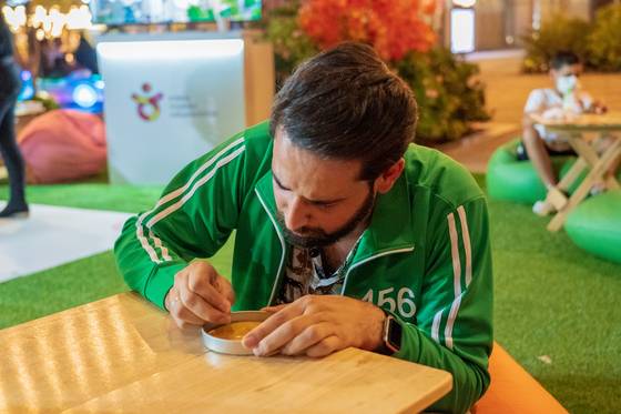 A visitor tries to carve out a shape from dalgona, a thinly spread Korean sugar candy with a stamped outline of a random shape, at a booth in Palm Jumeirah, Dubai. The Korea Tourism Organization hosted the booth as part of "Feel Korea 2021," which ran from Oct. 14 to 16. The event showcased various games and products related to Korean culture, including the popular dalgona featured in "Squid Game." [YONHAP]