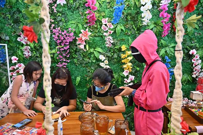 자카르타의 오징어게임 테마카페에서 달고나 만들기를 체험하는 손님/AFP연합뉴스