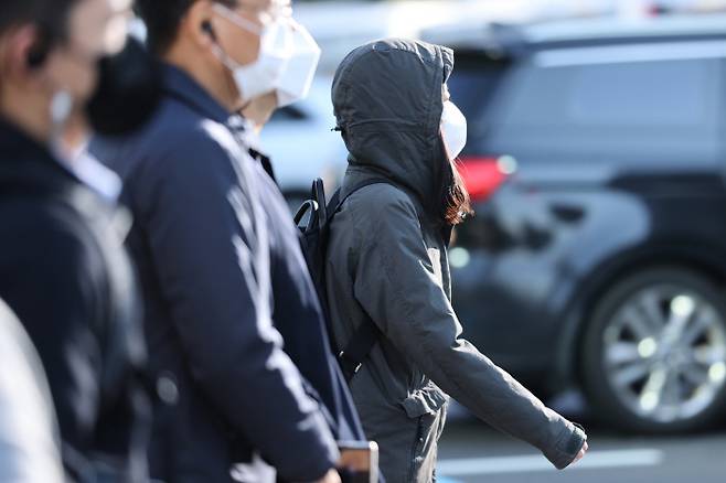 아침 기온이 5도까지 내려가 쌀쌀한 날씨를 보인 20일 오전 서울 종로구 광화문네거리에서 외투 모자를 눌러 쓴 시민이 발걸음을 옮기고 있다. [사진 출처 = 연합뉴스]