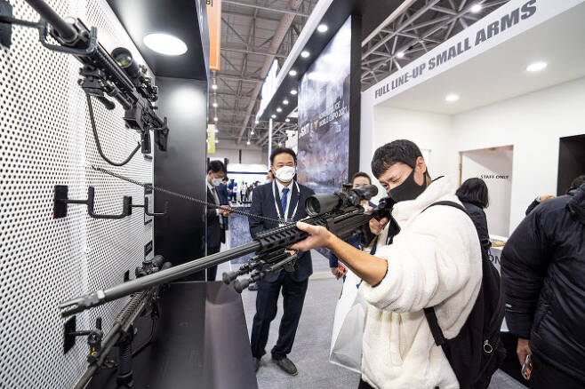 SNT모티브가 오는 22일까지 인천 송도 컨벤시아에서 열리는 ‘제3회 국제치안산업박람회’(KPEX 2021)에 참가한 가운데 SNT모티브 전시 부스를 찾은 방문객이 7.62㎜ K-14 저격용 소총을 들어 조준경을 보고 있다(사진=SNT모티브 제공).