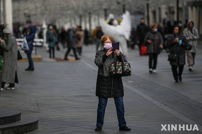 [모스크바=신화/뉴시스] 20일(현지시간) 러시아 모스크바 거리에서 마스크를 쓴 한 여성이 사진을 찍고 있다. 2021.10.21.
