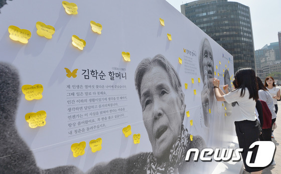 12일 오전 시청 앞 서울광장에 설치된 위안부 할머니 사진과 생전 남긴 말씀을 담은 '아트월'에 시민들이 응원의 메시지를 붙이고 있다. 아트월에는 최초로 위안부 증언을 한 김학순 할머니와 일본정부의 사과를 촉구하는 운동을 벌이다 세상을 떠난 황금주, 강덕경 할머니의 얼굴 사진이 걸려있다. 2015.8.12/뉴스1 © News1 박세연 기자