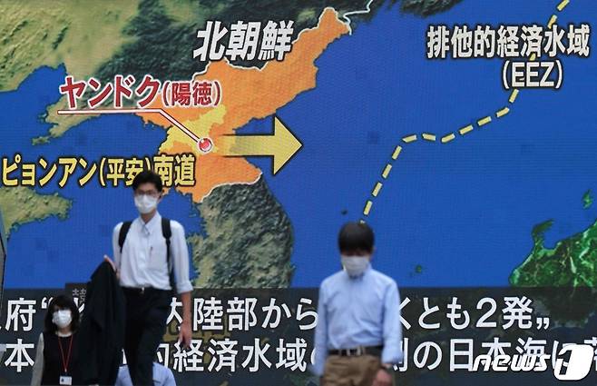 지난달 16일 일본 도쿄 아키하바라에서 시민들이 북한의 철도기동미사일연대 사격훈련(9월15일) 소식을 전하는 대형 전광판 앞을 지나가고 있다. © AFP=뉴스1