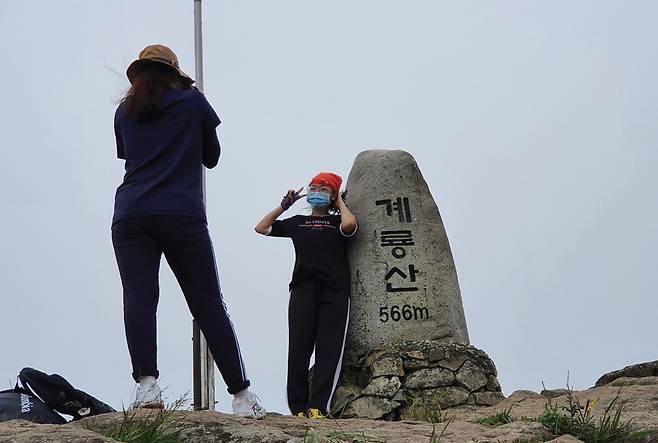 계룡산 정상석에서 젊은 여성 둘이 기념사진을 찍고 있다.