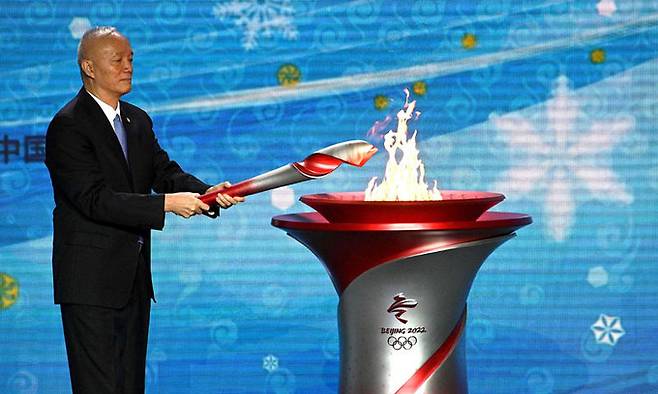 차이치 중국 베이징시 당서기 겸 2022 베이징동계올림픽 조직위원회 주석이 지난 20일 베이징에서 열린 성화 환영식에서 건네받은 성화를 성화대에 점화하고 있다. 베이징=AFP연합뉴스