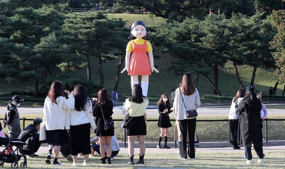 지난 25일 오후 서울 송파구 올림픽공원 야외 88잔디마당에 설치된 넷플릭스 드라마 ‘오징어 게임’ 속 영희 로봇 동상이 시민들 눈길을 끌고 있다.  뉴스1