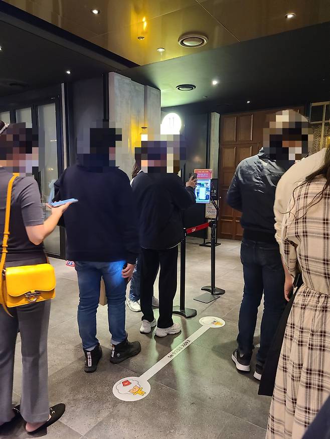 Moviegoers line up to scan QR codes proving they are fully vaccinated before entering a vaccine-pass auditorium at CGV Yongsan in central Seoul on Saturday night. (Song Seung-hyun/The Korea Herald)