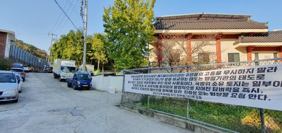 부산 수영구 광안3구역재개발추진위(가칭)가 정비구역 내 진입로로 계획 중인 토지의 모습. 현수막 뒤로 금련사의 법당이 보인다. 사진=정용부 기자