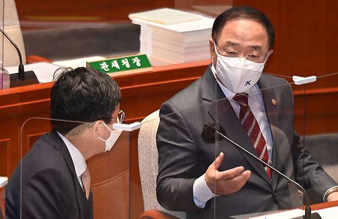 홍남기 경제부총리가 10일 국회 예산결산특별위원회 전체회의에서 정부 관계자와 대화하고 있다. 홍 부총리는 이날 전 국민 재난지원금 지급을 위해 올해 납부할 세금을 내년으로 유예하자는 여당의 주장은 “재난 위기 상황에서만 납부 유예를 허용하는 국세징수법에 저촉된다”고 했다. /국회사진기자단