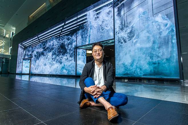 서울 마곡동 '더 넥센 유니버시티'에 설치된 디스트릭트의 영상 작품 앞에 앉은 이성호 대표. 투명 수조 안에서 진짜 파도가 출렁이는 듯한 모습을 시도한 첫 작품이다. /이신영 영상미디어 기자