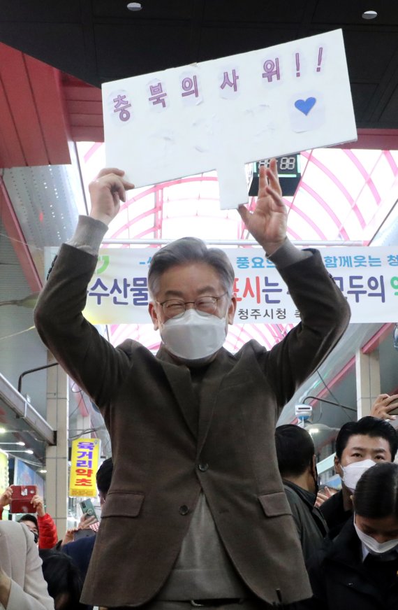 이재명 더불어민주당 대선 후보(오른쪽)와 부인 김혜경씨가 21일 오전 충북 청주시 육거리종합시장을 방문해 '충북의 사위'라고 쓰여진 피켓을 들고 상인 및 지지자들에게 인사를 나누고 있다. 뉴스1