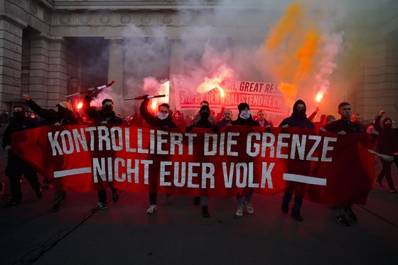 20일(현지시간) 오스트리아 수도 비엔나에서 코로나19 봉쇄 정책에 반대하는 시위자들이 횃불을 들고 구호를 외치고 있다. 현수막에는 '당신의 국민들이 아닌 국경을 통제하라'는 문구가 적혀 있다. [AP=연합뉴스]