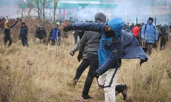 폴란드와 접경한 벨라루스 그로드노에서 16일(현지시간) 중동 출신 난민들이 폴란드 국경경비대와 충돌하는 가운데 한 난민 남성이 돌을 던지고 있다. 그로드노= AP·벨타연합뉴스