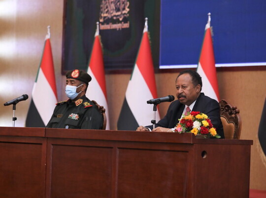 수단의 압달라 함독 총리(오른쪽)와 군부 최고권력자 압델 파타 알부르한이 21일 권력분점에 합의하는 문서에 서명한 뒤 함께 앉아 있다. Republican Media Palace 배포. 하르툼/EPA 연합뉴스