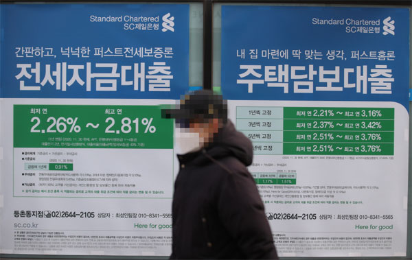 25일 한국은행 금융통화위원회가 기준금리를 0.25%포인트 인상해 1.00%로 정한 가운데 한 시민이 은행에 게시된 전세자금·주택담보대출 안내 표지판 앞을 지나고 있다. [연합뉴스]