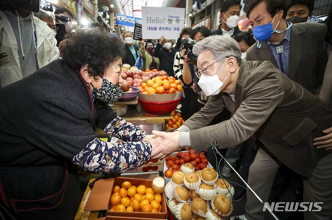 [청주=뉴시스] 정병혁 기자 =  이재명 더불어민주당 대선 후보와 부인 김혜경 씨가 21일 오후 충북 청주시 육거리종합시장을 찾아 과일을 구매하고 있다. 2021.11.21. jhope@newsis.com