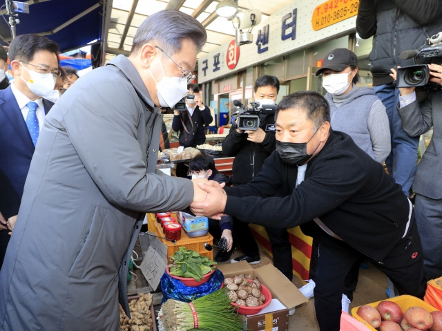 더불어민주당 이재명 대선 후보가 28일 광주시 광산구 송정시장에서 한 상인과 인사하고 있다. 연합뉴스.