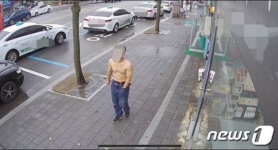 한 40대 남성이 한낮에 부여읍 시가지 한복판에서 상의를 탈의한 채 한 손에는 흉기를 들고 걸어가고 있다.(독자제공)/사진 =  뉴스1