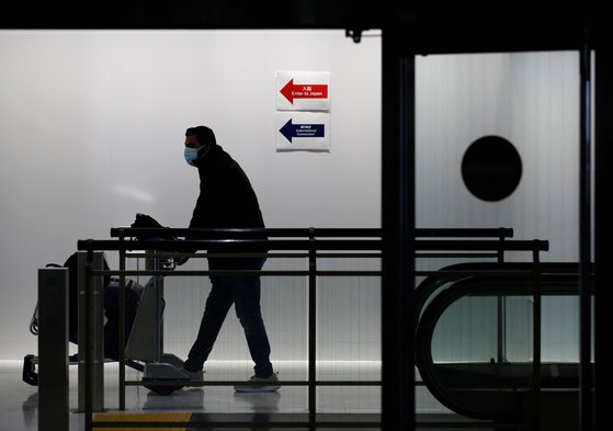 일본이 오미크론 유입을 막기 위해 외국인 신규 입국 전면 금지를 발표한 지난달 30일, 마스크를 쓴 승객이 나리타 공항을 지나고 있다. [로이터=연합뉴스]