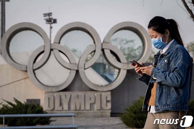 중국 베이징에서 한 여성이 올림픽 조각상 앞을 지나고 있다. 2020.03.23 © AFP=뉴스1