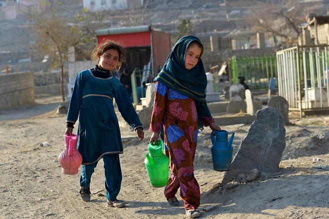 아프가니스탄 소녀들이 1일(현지시간) 슈하다 호수 인근의 묘지에서 물을 팔기 위해 방문자들을 찾고 있다. 연합뉴스